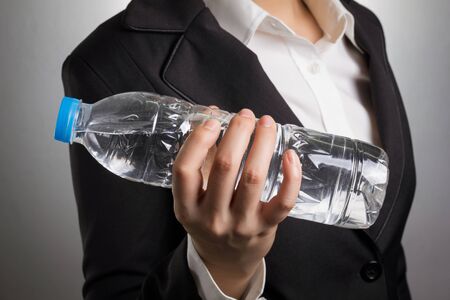 Close up business woman body in black suit with hand holding bottle of water.の写真素材