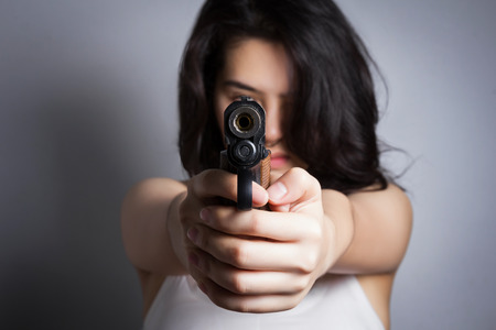 Woman aiming a gun,focus on the gun.の写真素材
