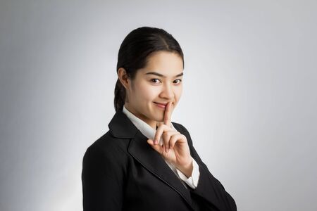 Young Asian businesswoman with her finger on her lips - quiet.