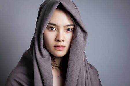 Young Asian woman with grey fabric cover her head.の写真素材