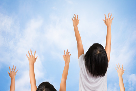 The Kids jumping and raise their arms in the air cross blue sky and clouds.の写真素材