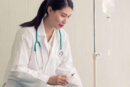 Beautiful female doctor in white medical coat is consulting her patient, showing the result of health check.の写真素材