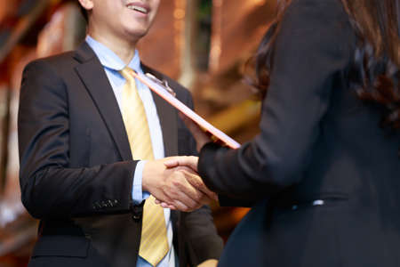 Close up cropped Asian businessman hand shaking teethe smile with business woman, dealing investing...