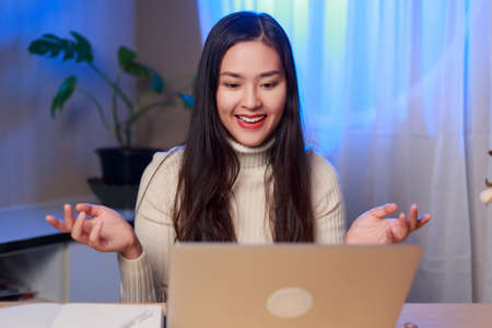Young beauty happy Asian woman making video call talking trough webcam at night. Asian female...