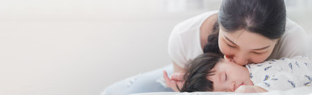 Close up portrait of young beauty Asian mother kissing her newborn baby boy while he sleep. Healthcare and medical insurance. Asia mother's day concept bannerの写真素材