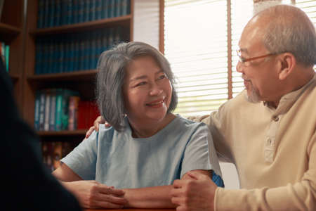 Happy Asian senior couple feel releif and pleasant after get the advice about family financial planning from professional financial advisor at home.の写真素材
