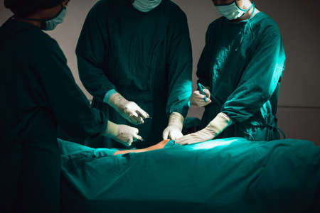 Asian Medical Team Performing Surgical Operation in Modern Operating Room. Doctors and Nurse in...