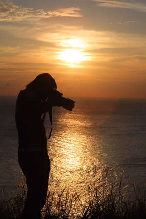 Photographer silhouette shooting sea outdoors at sunset background