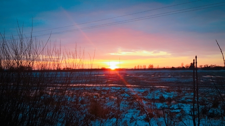 Sunset over snow-covered fieldの写真素材