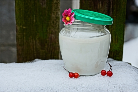 Glass jar with milk, viburnum berries on the snowの写真素材