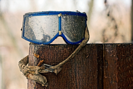Old ski goggles in dust standing on wooden boardsの写真素材