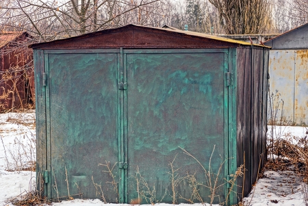 Old metal green garage in the yard in the snowの写真素材