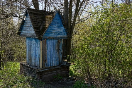 old blue wooden well in the yard amongst the bushes and treesの写真素材