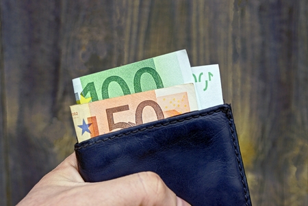 The purse and money in hand on grey wooden background