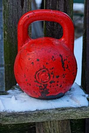 Red weights on a wooden bench in the snowの写真素材
