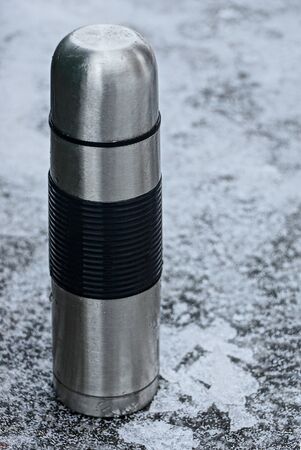 Gray iron water bottle standing in the snowの写真素材