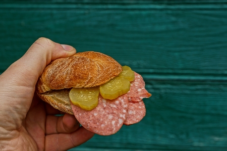 Sandwich with sausage and a cucumber on a green backgroundの写真素材