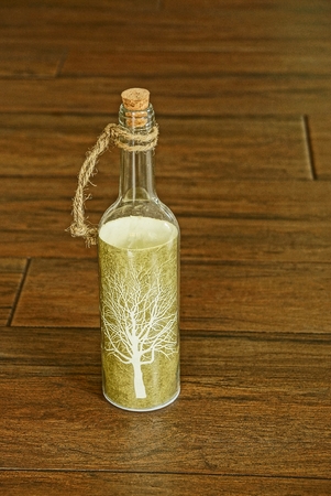 Glass bottle with a picture on the label, standing on the brown floorの写真素材
