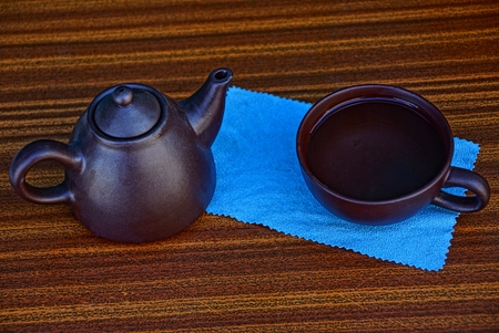 Brown teapot and cup standing on a tableの写真素材