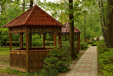 Brown arbors among vegetation in a theme park near the pavement pathの写真素材