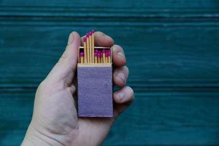 Box of matches in hand against the background of green wallの写真素材