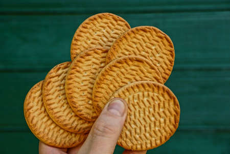 Round cookies in hand against the green wooden wallの写真素材