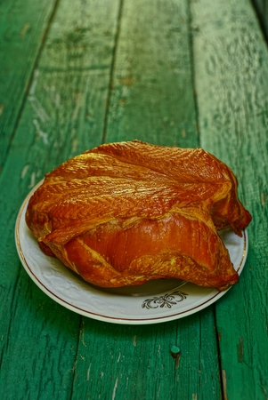 Smoked chicken on a plate stands on wooden green boardsの写真素材