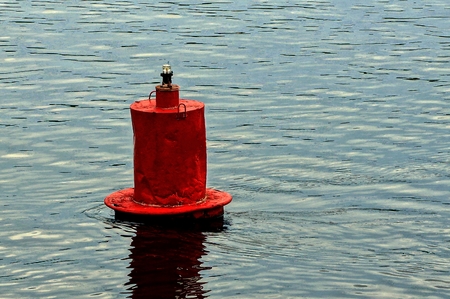 Red iron buoy in the water of the riverの写真素材