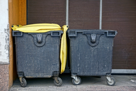Two garbage containers near the wall