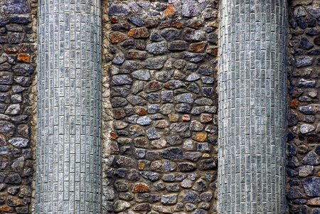 The texture of the stone from the wall of colored cobblestones and brick columns