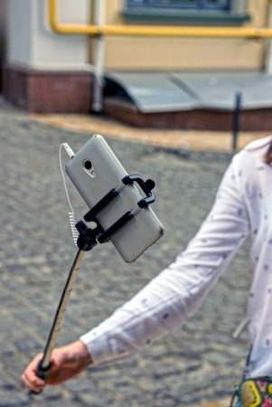 Gray smartphone on monopod in girl's handの写真素材