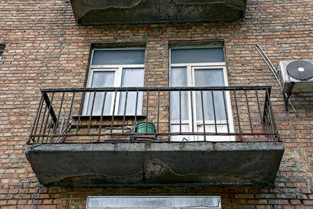 An old balcony with a window and a door on the brown wall of the houseの写真素材