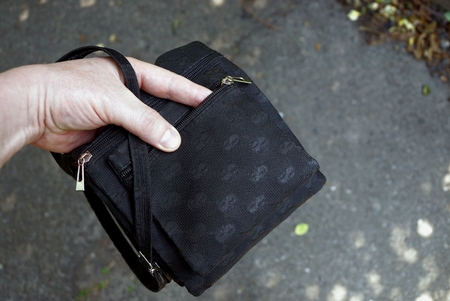 Hand in an open small black bag on the streetの写真素材