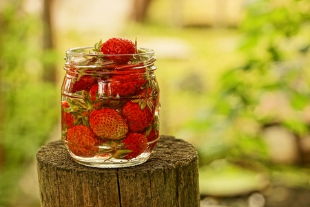 Glass jar with strawberries in water on a wooden stumpの写真素材