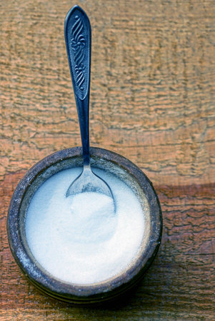 Spoon full of salt in a hodgepodge on a brown wooden tableの写真素材
