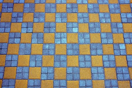 Texture of colored square paving tiles on the road