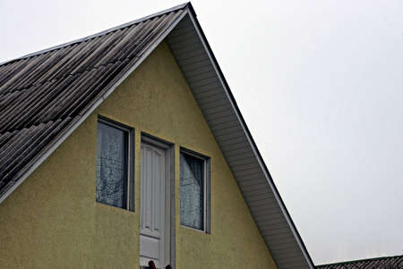 Facade of a building with a window door and slate roofの写真素材