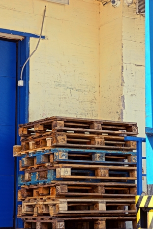 Old wooden pallets stand against the wall of the buildingの写真素材