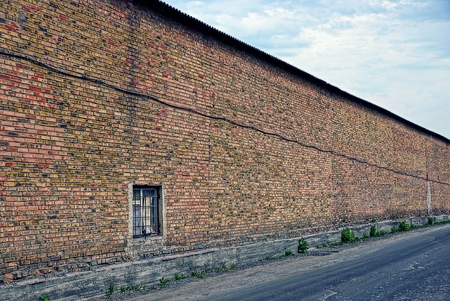 Long brown brick wall along asphalt roadの写真素材