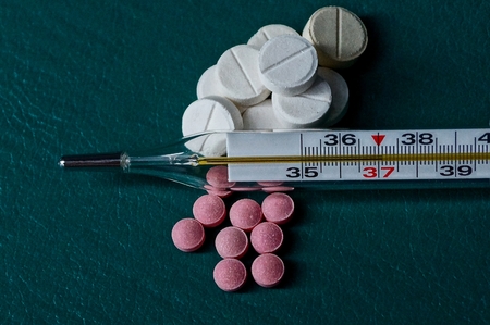 Thermometer and pills on a green backgroundの写真素材