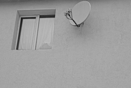 Window and a satellite dish on a gray wallの写真素材