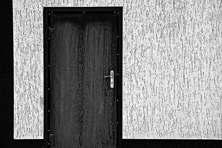 Black closed door on the wall of a gray private houseの写真素材