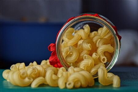 Dry yellow pasta in a glass jarの写真素材