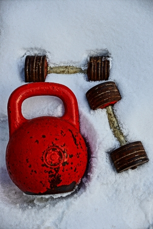 Old weights and dumbbells in the snow on the sports fieldの写真素材