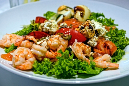 Shrimp salad with cheese and greens tomatoes in a plateの写真素材