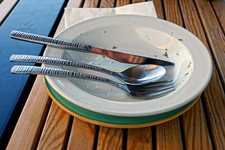 Dirty dishes with cutlery on a brown wooden tableの写真素材