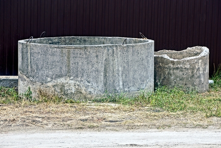 Two old concrete rings in the yard near the fenceの写真素材