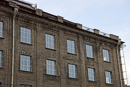 gray facade of an old high-rise building with windows on the sky background