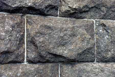 The gray wall of a large house made of large stone bricks