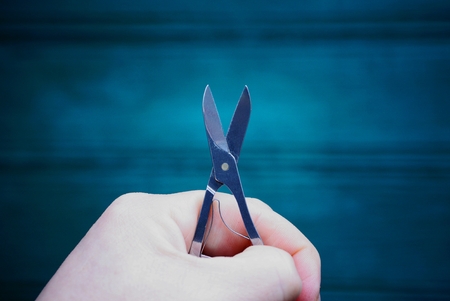 small iron scissors in a hand on a green background